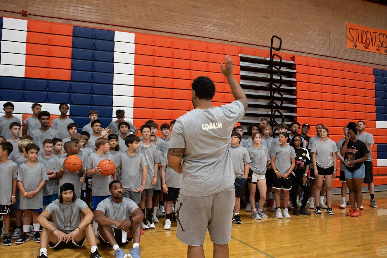 Coach CJ addressing a large group of camp players in the gym