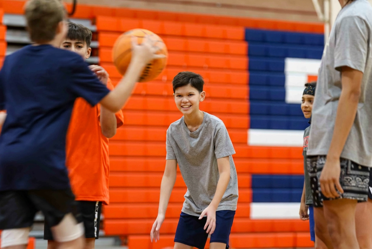Young girl smiling while dribbling a basketball during practice