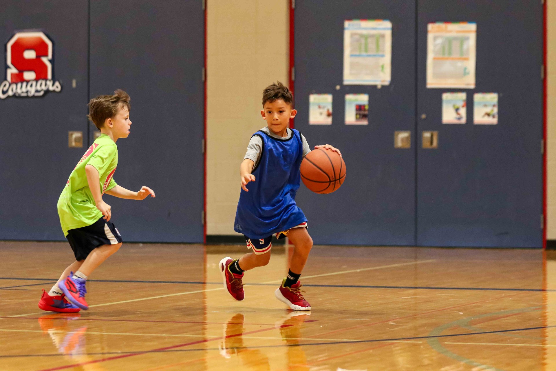 Young player driving the basketball past a defender in the gym